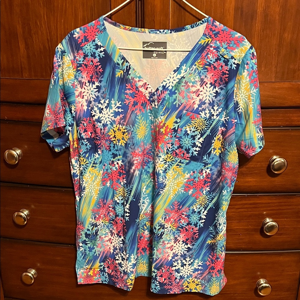Butter-soft stretch snowflake print scrub top. Has 1 chest pocket.